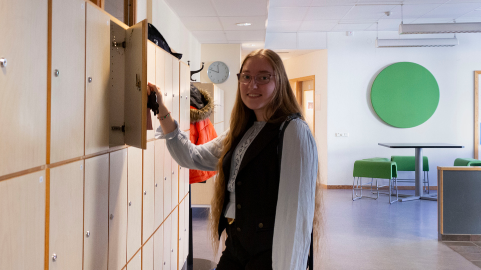 Foto som visar den tidigare eleven Linnéa Andersson vid ett av elevskåpen på skolan. 